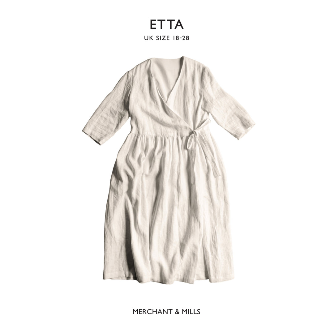 An off-white linen wrap dress with three-quarter sleeves and a tie waist, shown flat against a white background with brand text 'ETTA' and 'MERCHANT & MILLS'.