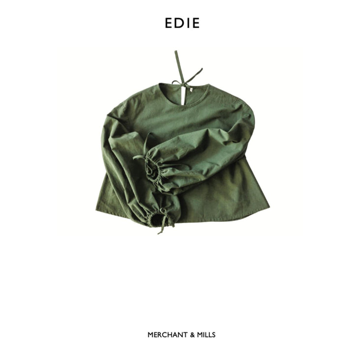 Green top with ruffled sleeves on a white background, featuring the brand 'EDIE' and 'MERCHANT & MILLS'.