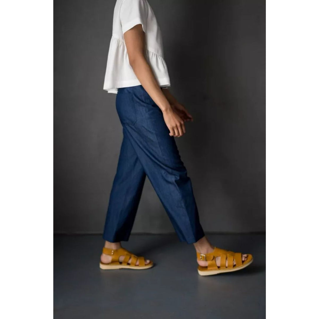 Person wearing blue pants and yellow sandals on a dark background