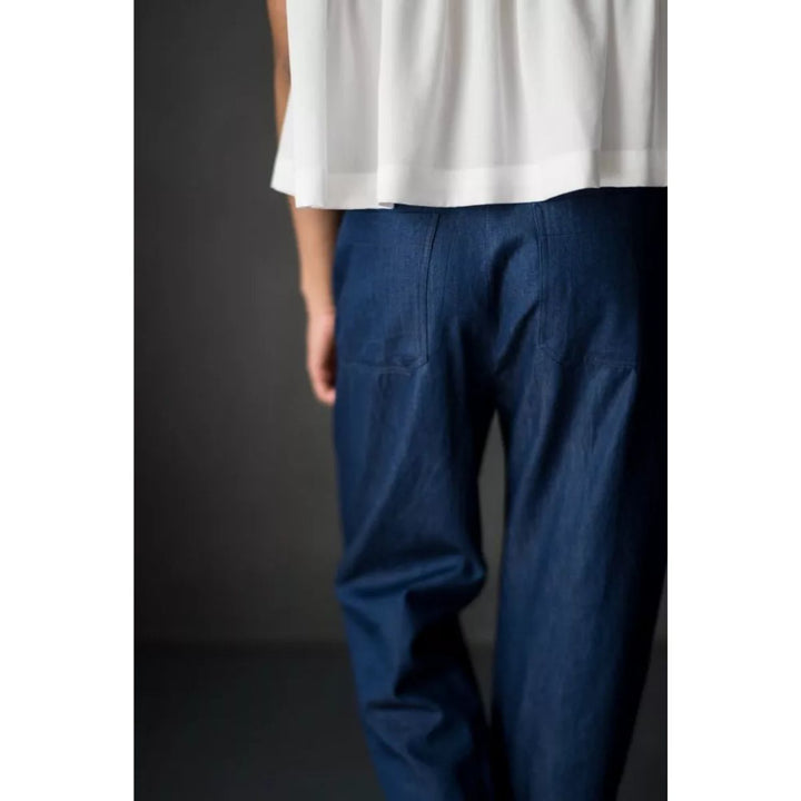 Person wearing a white top and blue pants on a dark background