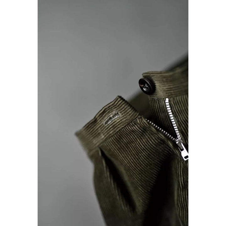 Green corduroy pants with a zipper on a gray background