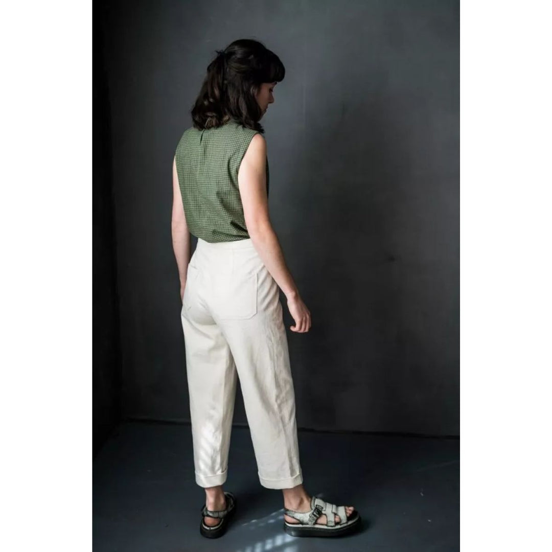 Person wearing a green top and beige pants against a dark background