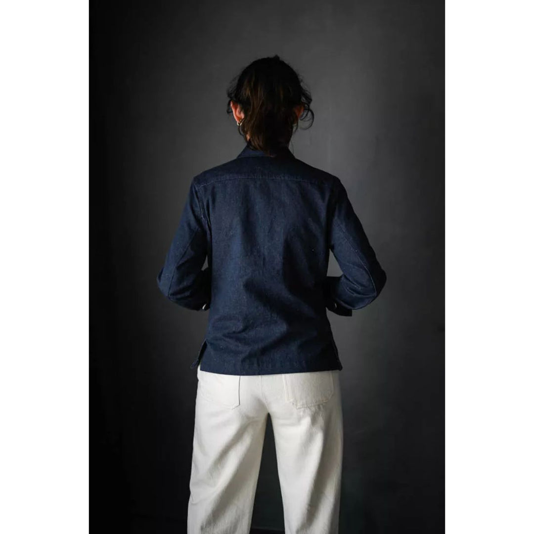 Person wearing a dark blue shirt and white pants against a dark background