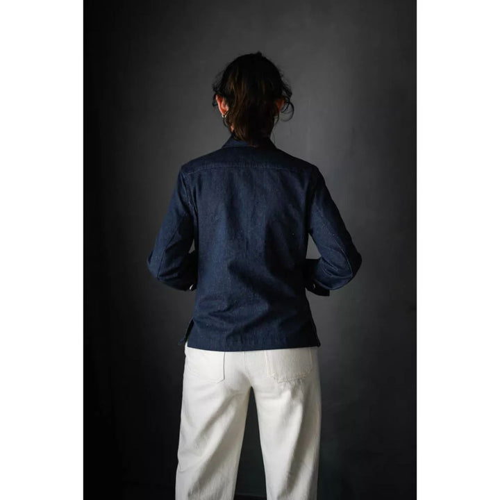 Person wearing a dark blue shirt and white pants against a dark background