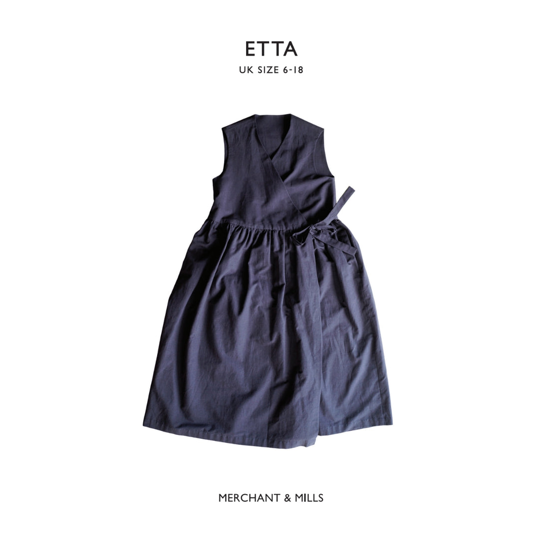 A sleeveless dark navy wrap-style dress with a gathered waist and tie detail, shown flat against a white background with text reading 'ETTA UK SIZE 6-18' at the top and 'MERCHANT & MILLS' at the bottom.