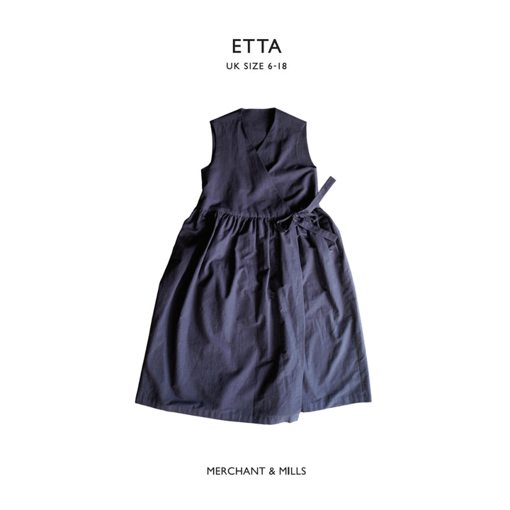 A sleeveless dark navy wrap-style dress with a gathered waist and tie detail, shown flat against a white background with text reading 'ETTA UK SIZE 6-18' at the top and 'MERCHANT & MILLS' at the bottom.