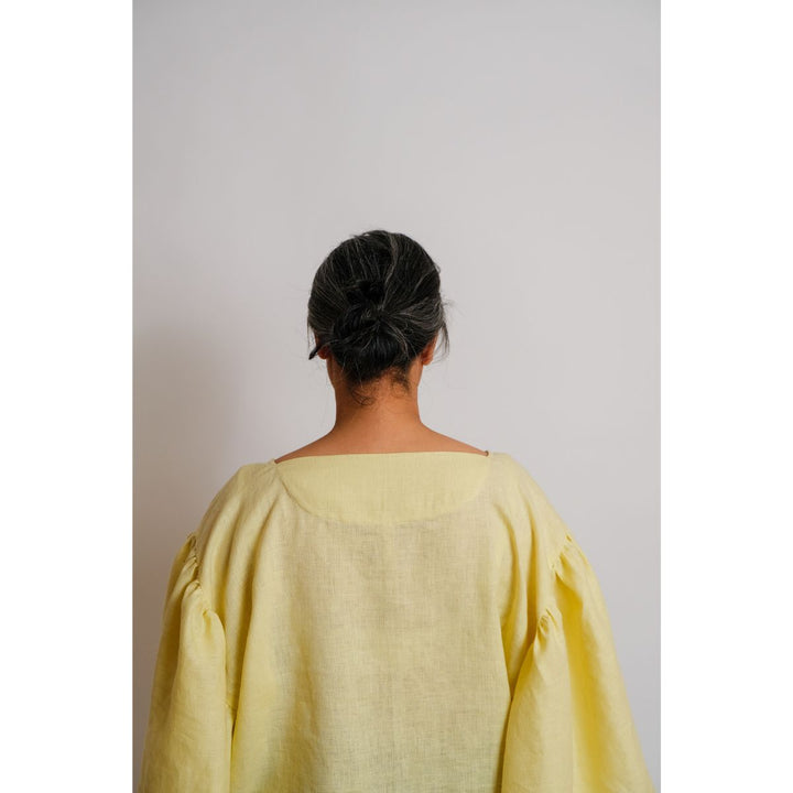 Person wearing a light yellow top against a plain background