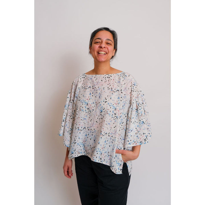 Person wearing a floral blouse against a plain background