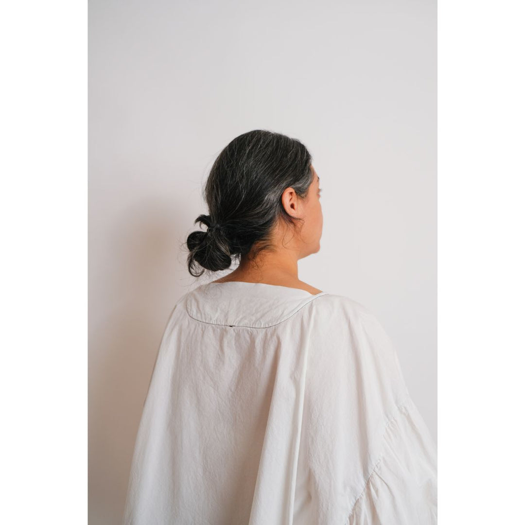 Person wearing a light-colored shirt against a plain background