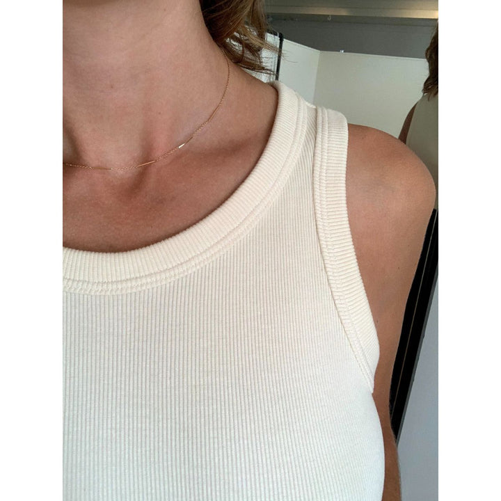 Close-up of a person wearing a white tank top with a blurred background