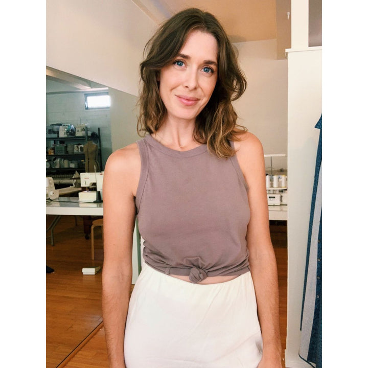 Woman wearing a sleeveless top and white pants indoors