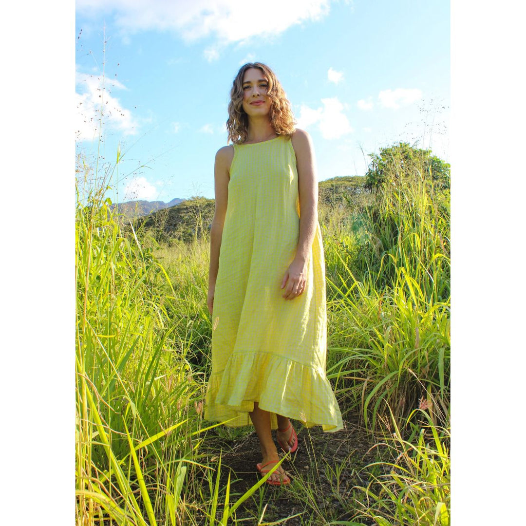Woman in a yellow dress standing in tall grass with a scenic background