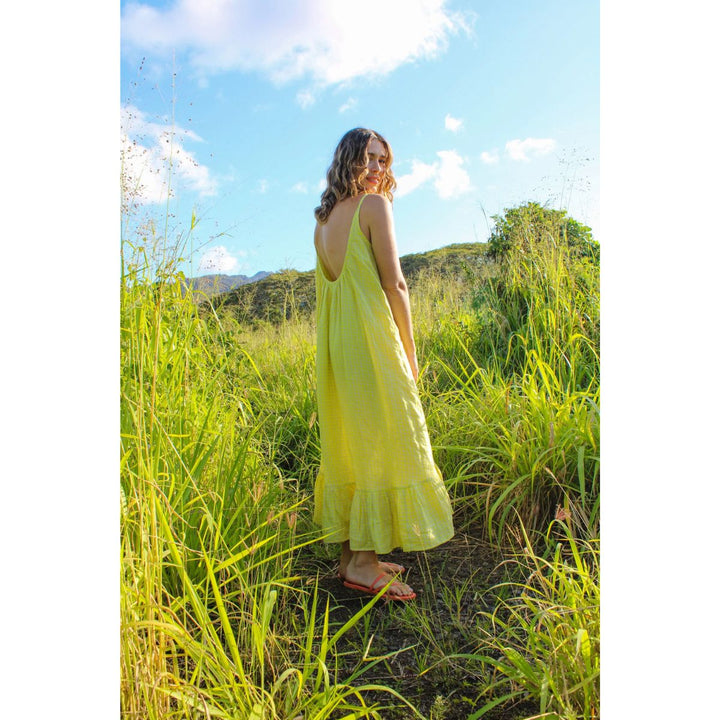 Woman in a yellow dress standing in tall grass with a scenic background