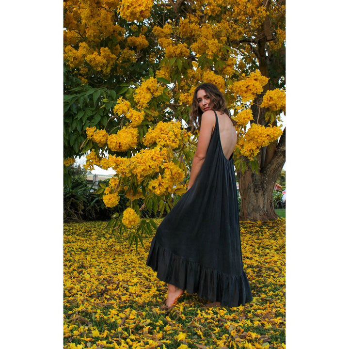 Woman in a black dress standing under a tree with yellow flowers