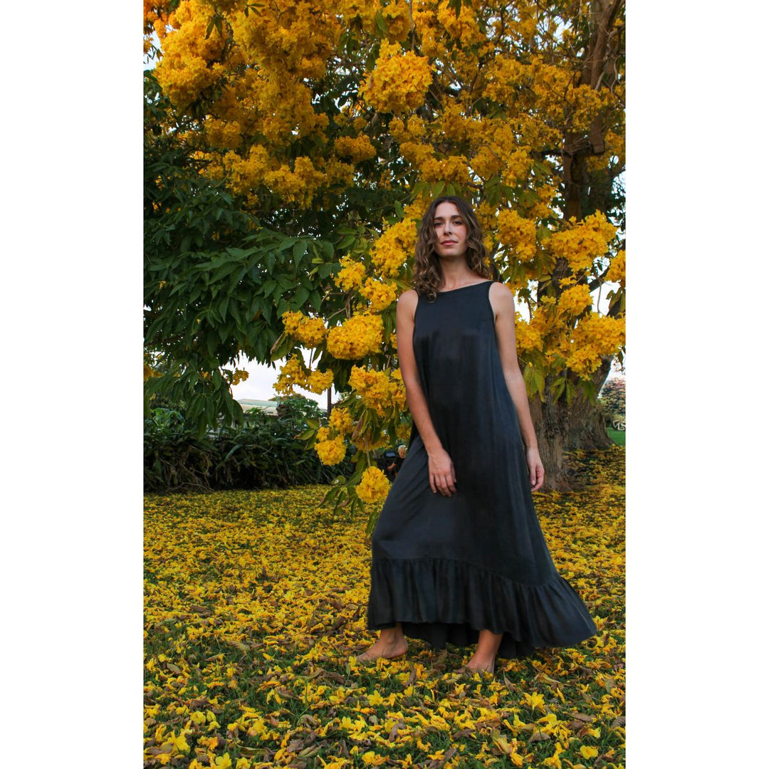 Woman in a black dress standing among yellow flowers and trees