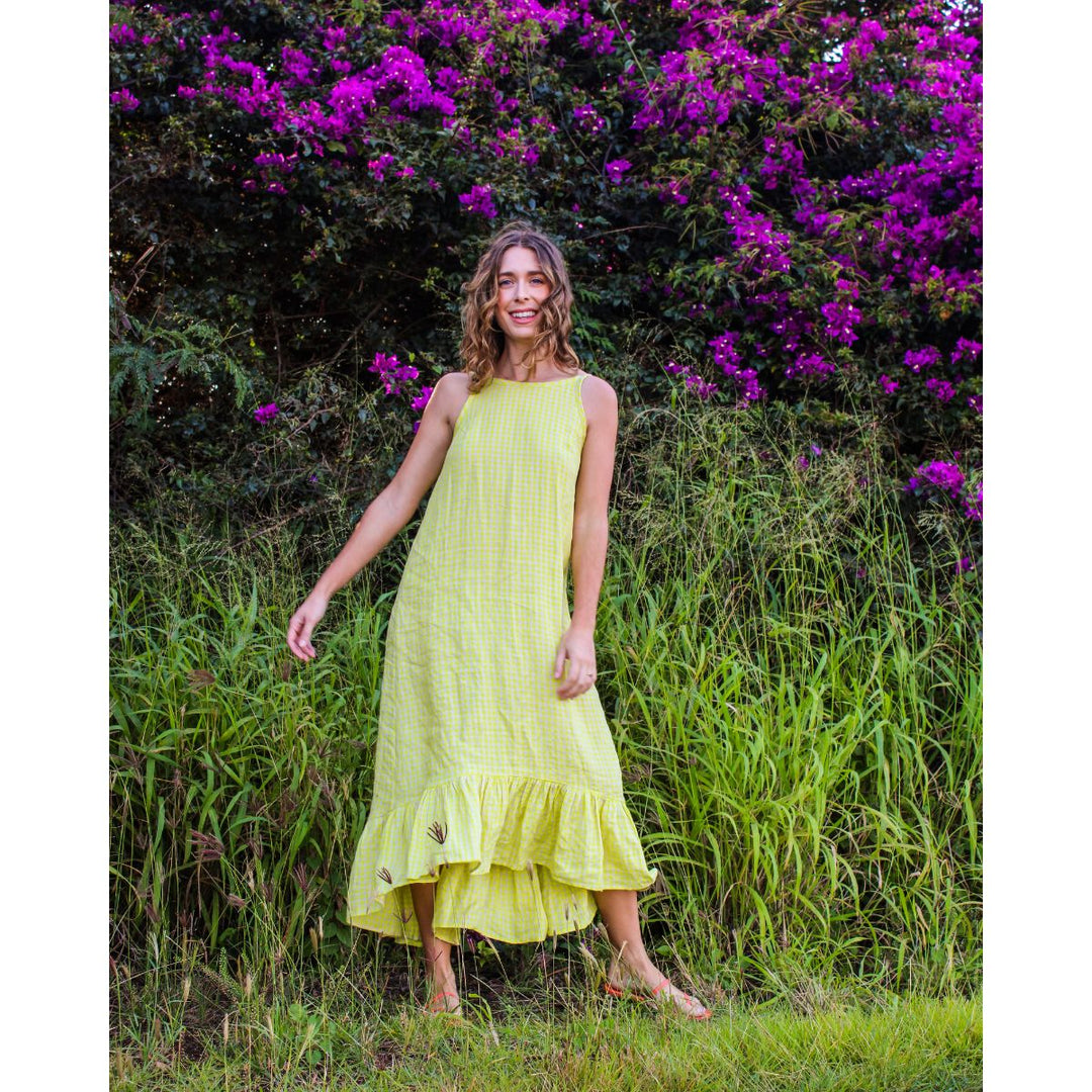 Woman in a yellow dress standing in a grassy area with purple flowers in the background