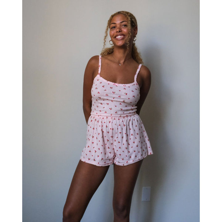Woman wearing a pink patterned romper against a plain wall