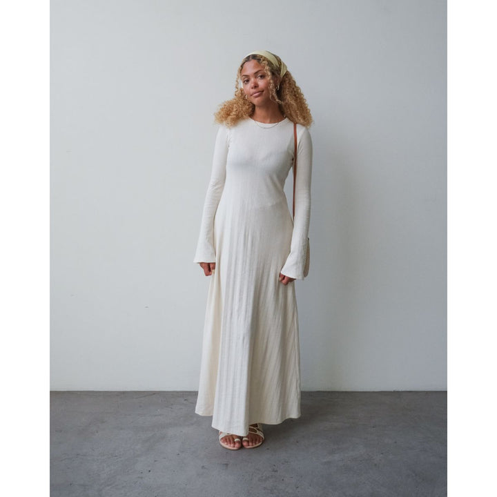 Woman wearing a long white dress against a plain background