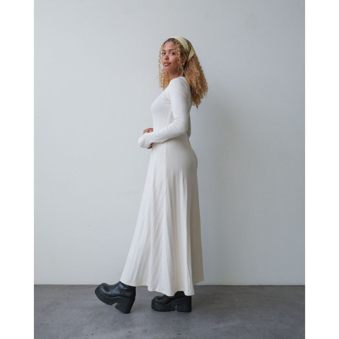 Woman wearing a long white dress against a plain background