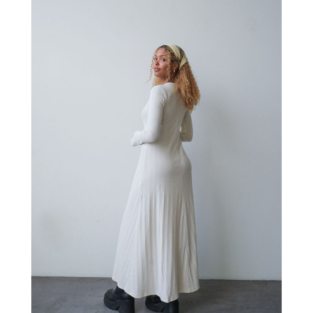 Woman wearing a long white dress against a plain background