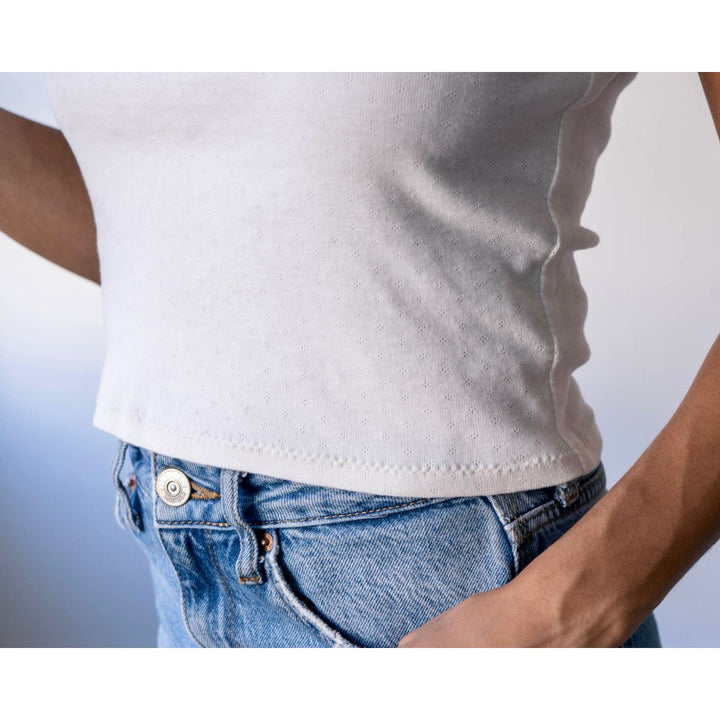Person wearing a white t-shirt and blue jeans against a light background
