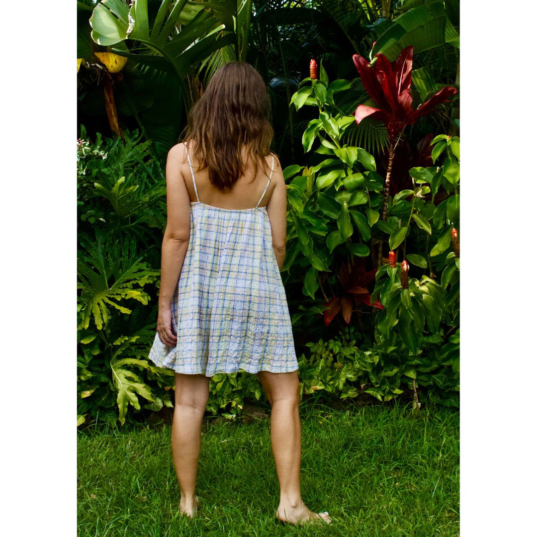 Woman in a checkered dress standing in a garden with lush greenery