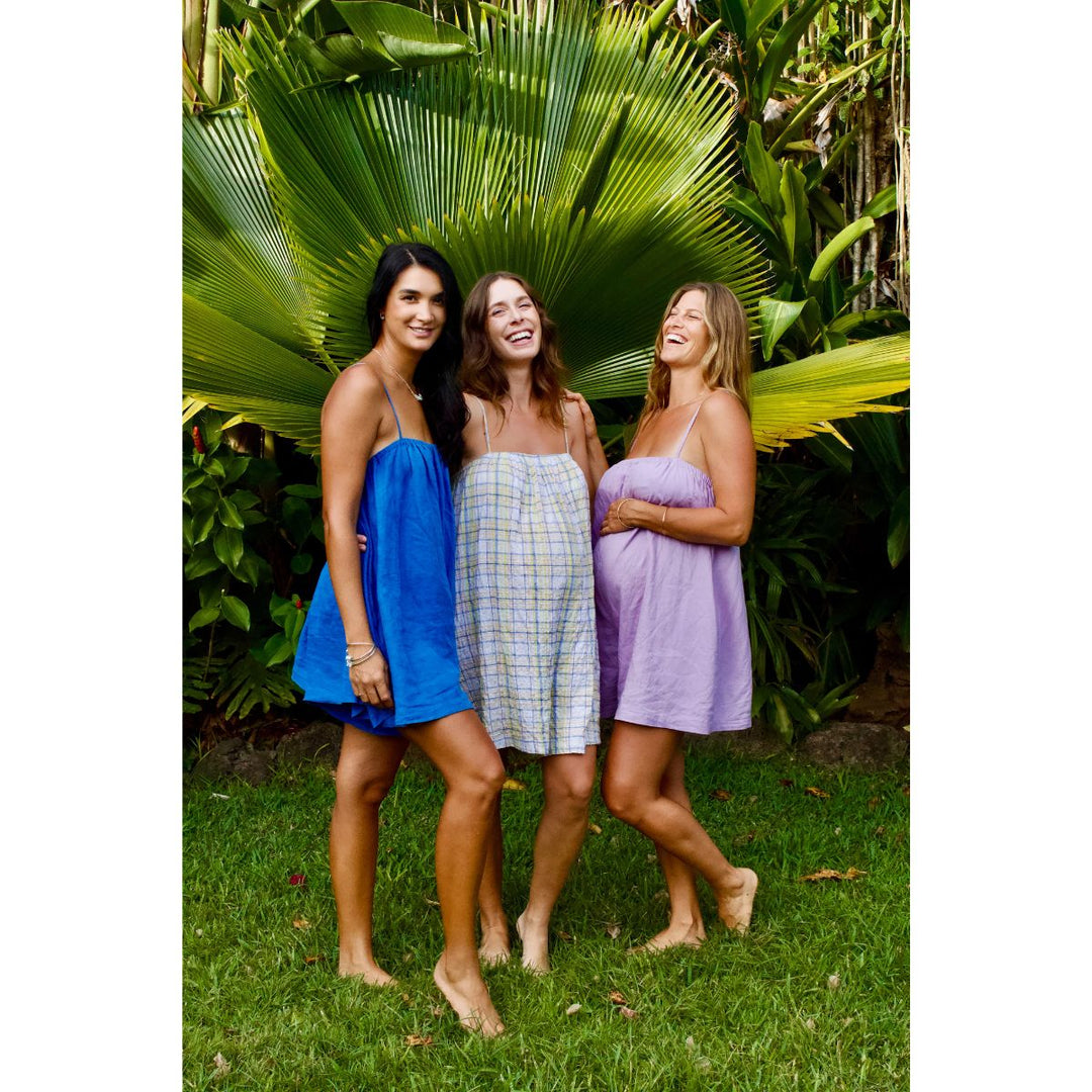 Three women standing together in front of tropical plants