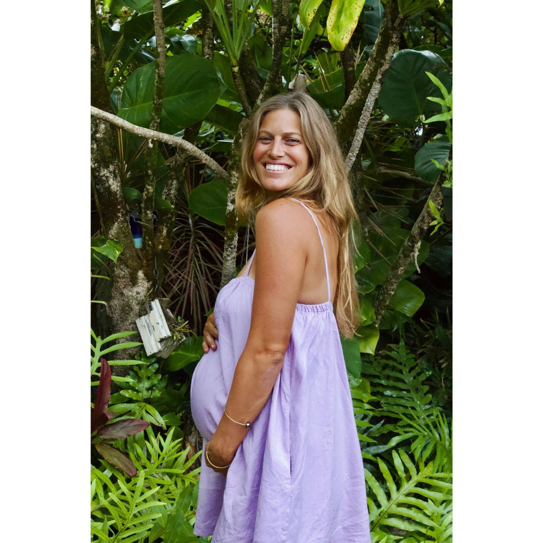 Woman in a purple dress standing among lush green foliage