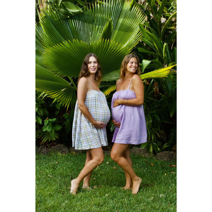 Two pregnant women standing outdoors with greenery in the background