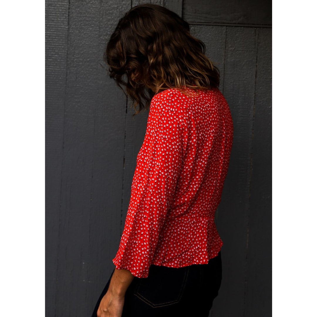 Person wearing a red polka dot blouse against a dark background