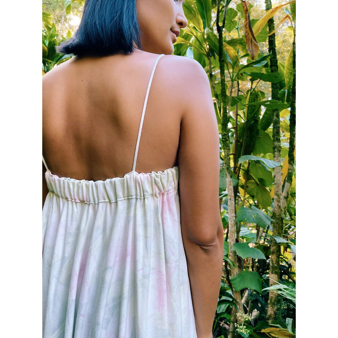 Person wearing a white dress with thin straps in a natural setting