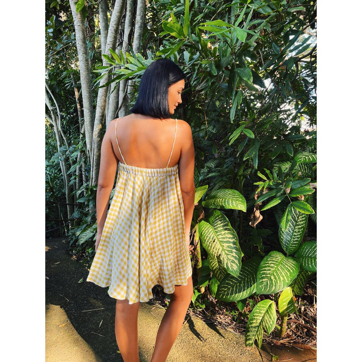 Woman in a yellow checkered dress standing in a tropical setting