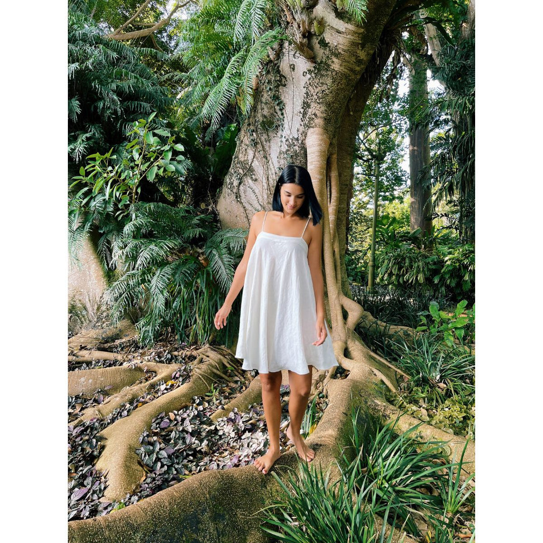Woman in a white dress standing in a lush, tropical forest.