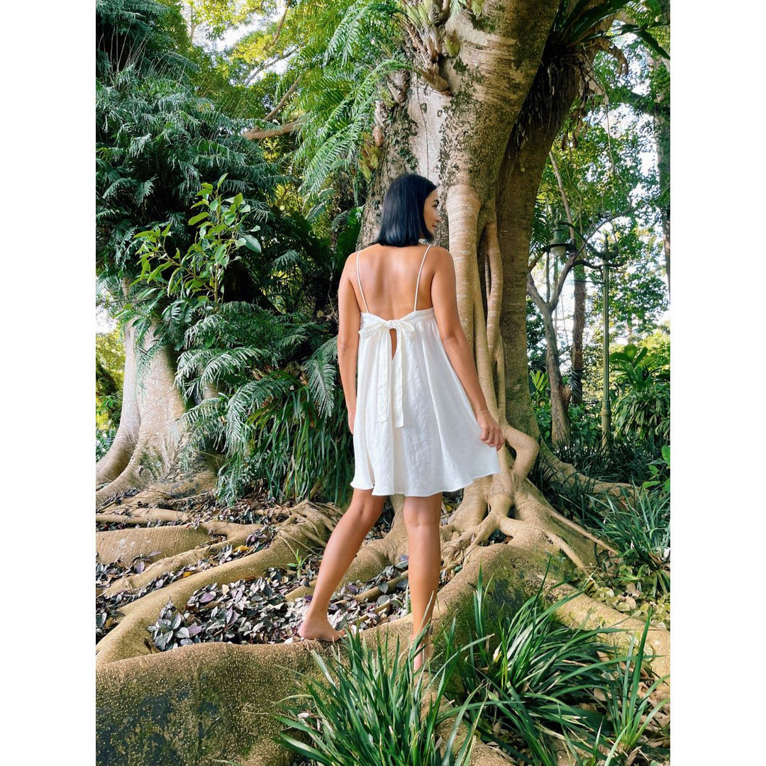 Woman in a white dress standing in a lush tropical forest