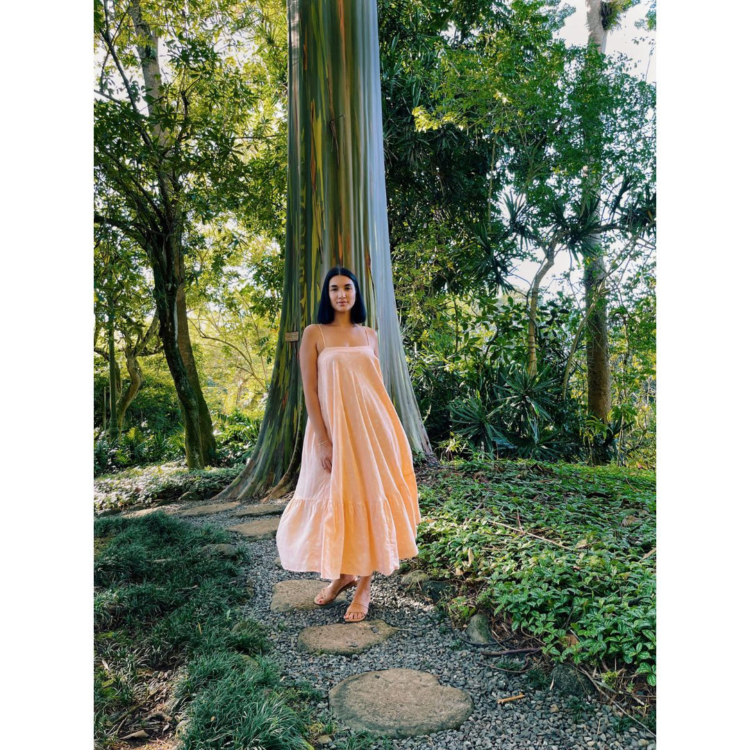 Woman in a peach dress standing on a path in a forest