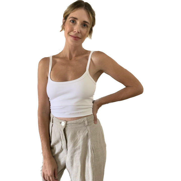 Woman wearing a white tank top and beige pants on a white background