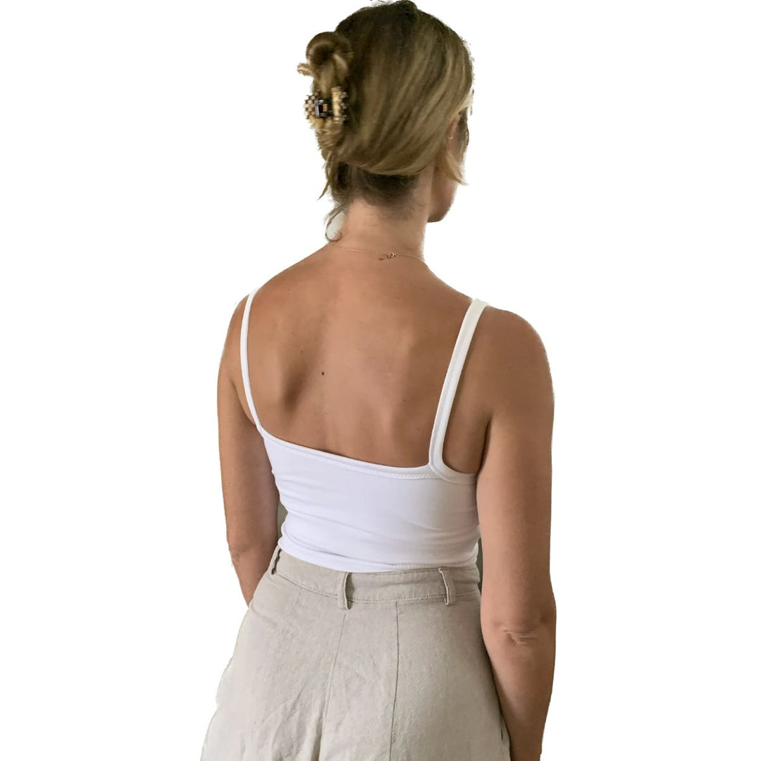 Woman wearing a white tank top and beige pants on a white background