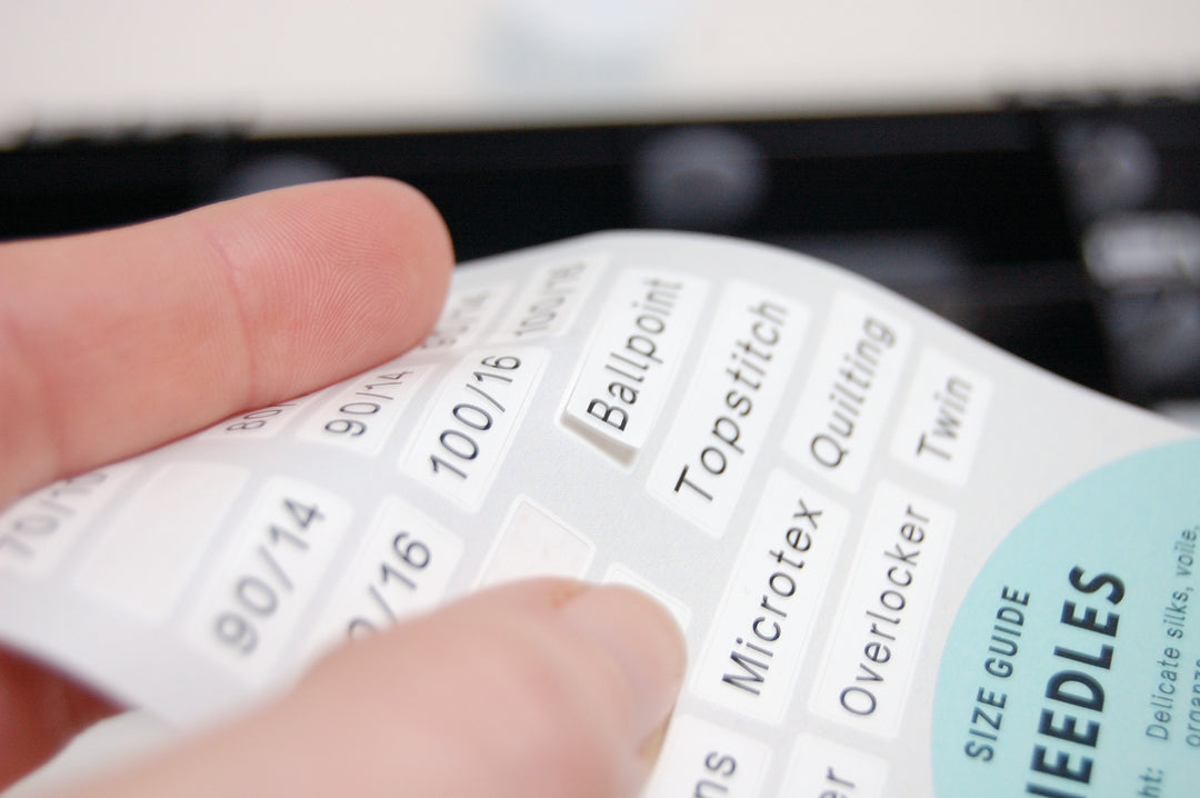 Close-up of a needle size chart with fingers pointing to a specific size.