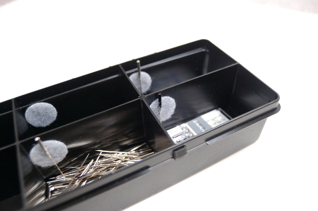 Black compartmentalized tray with various items on a white background