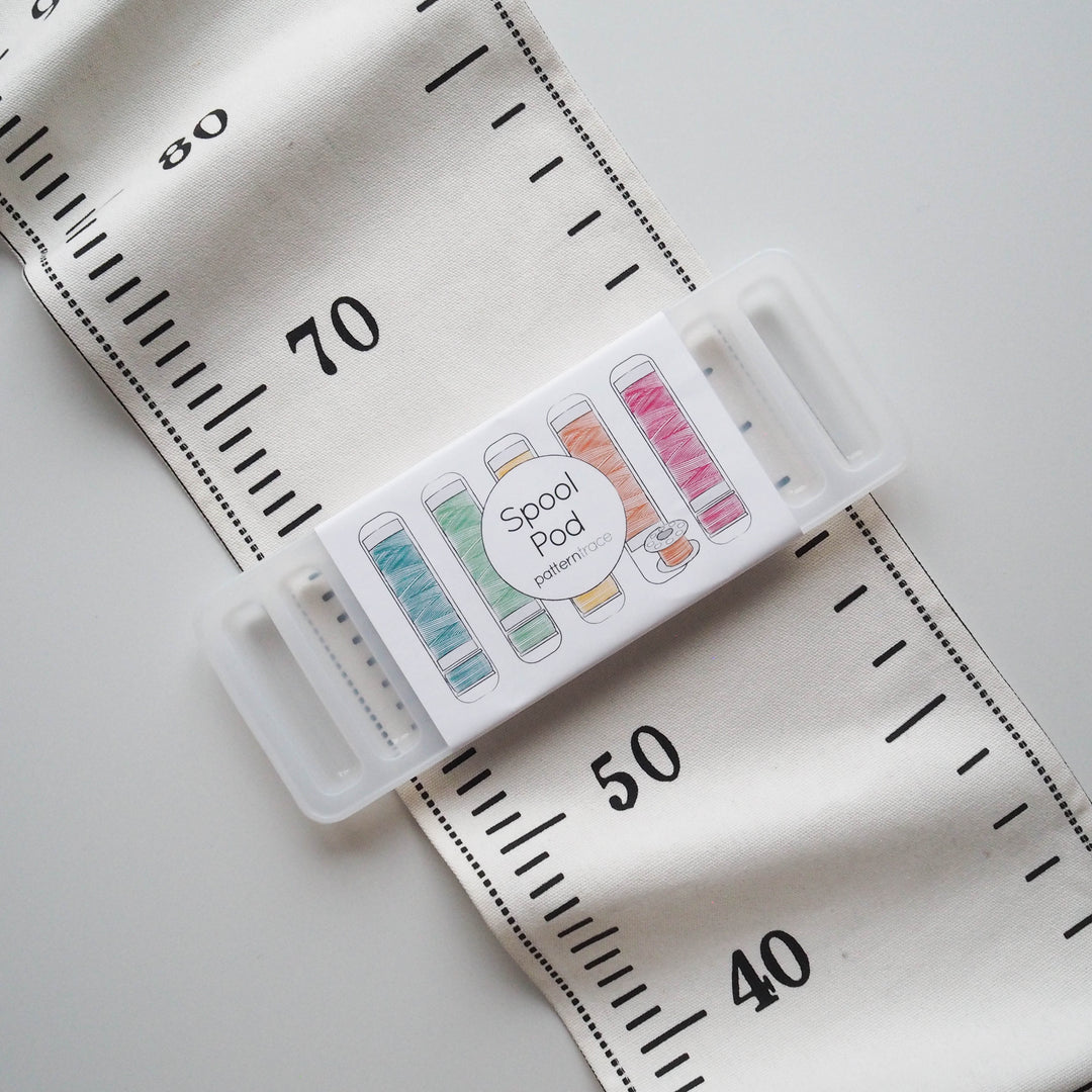 Spool Pod with colorful spools on a fabric background with measurement markings