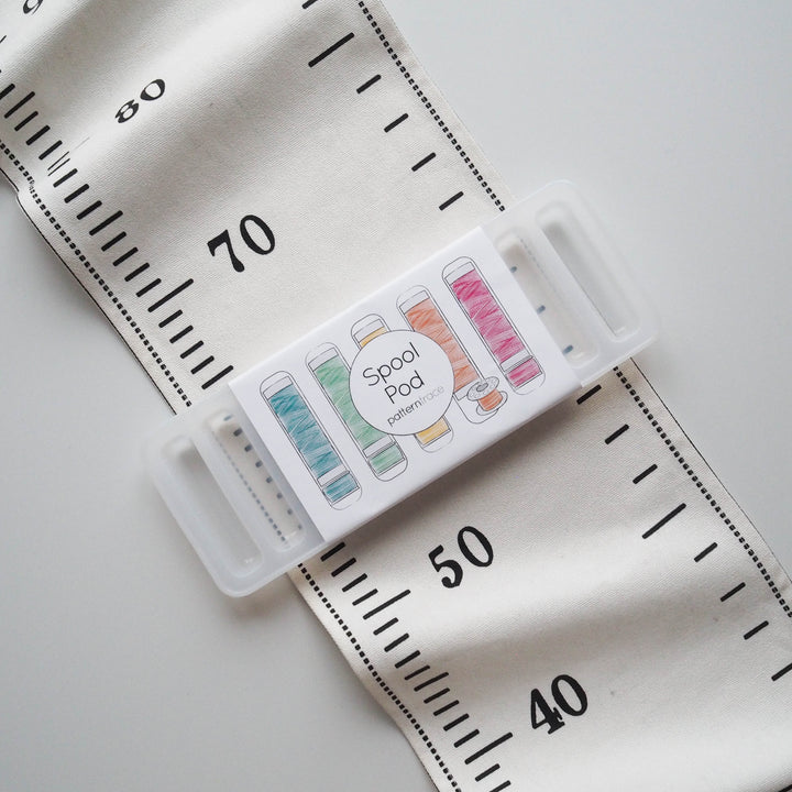Spool Pod with colorful spools on a fabric background with measurement markings