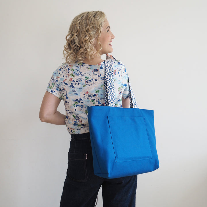 Woman holding a blue tote bag against a plain background