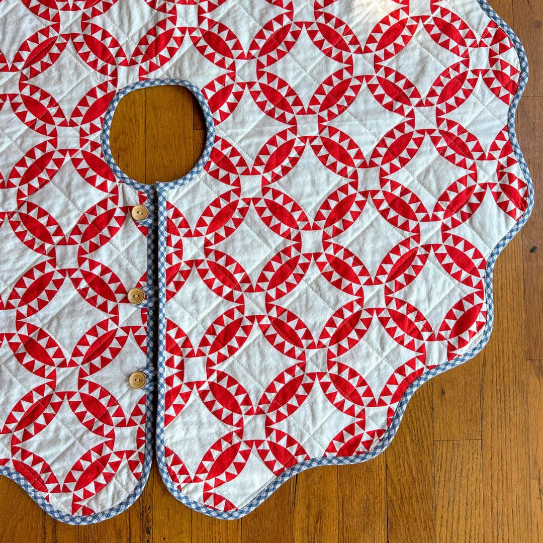 Quilted tree skirt with red and white geometric pattern on a wooden surface