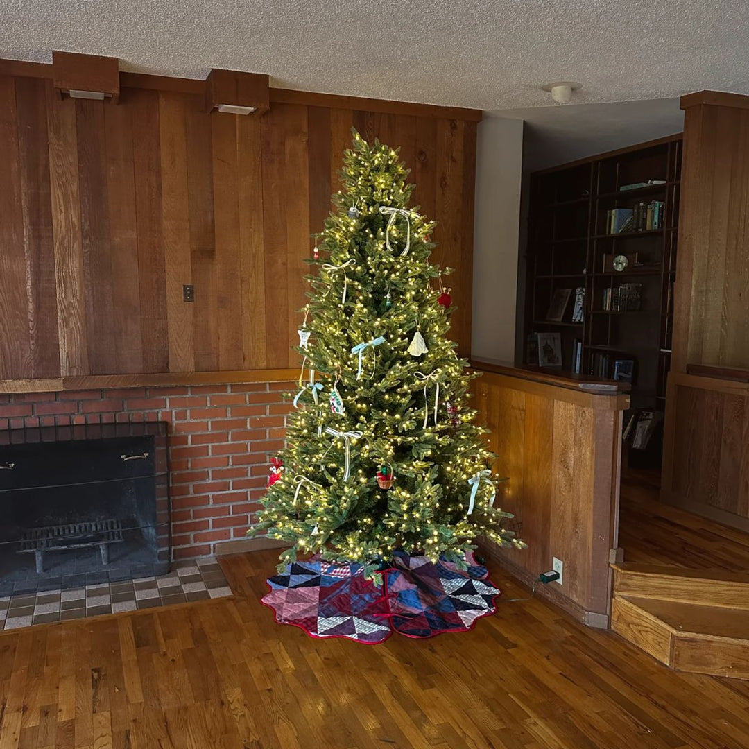 Decorated Christmas tree in a room with wooden paneling and a fireplace.