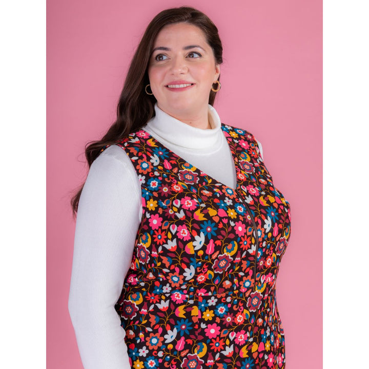 Woman wearing a colorful floral patterned vest against a pink background