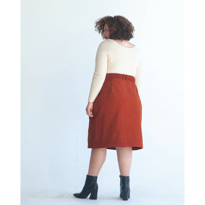 Person wearing a white top and rust-colored skirt on a white background