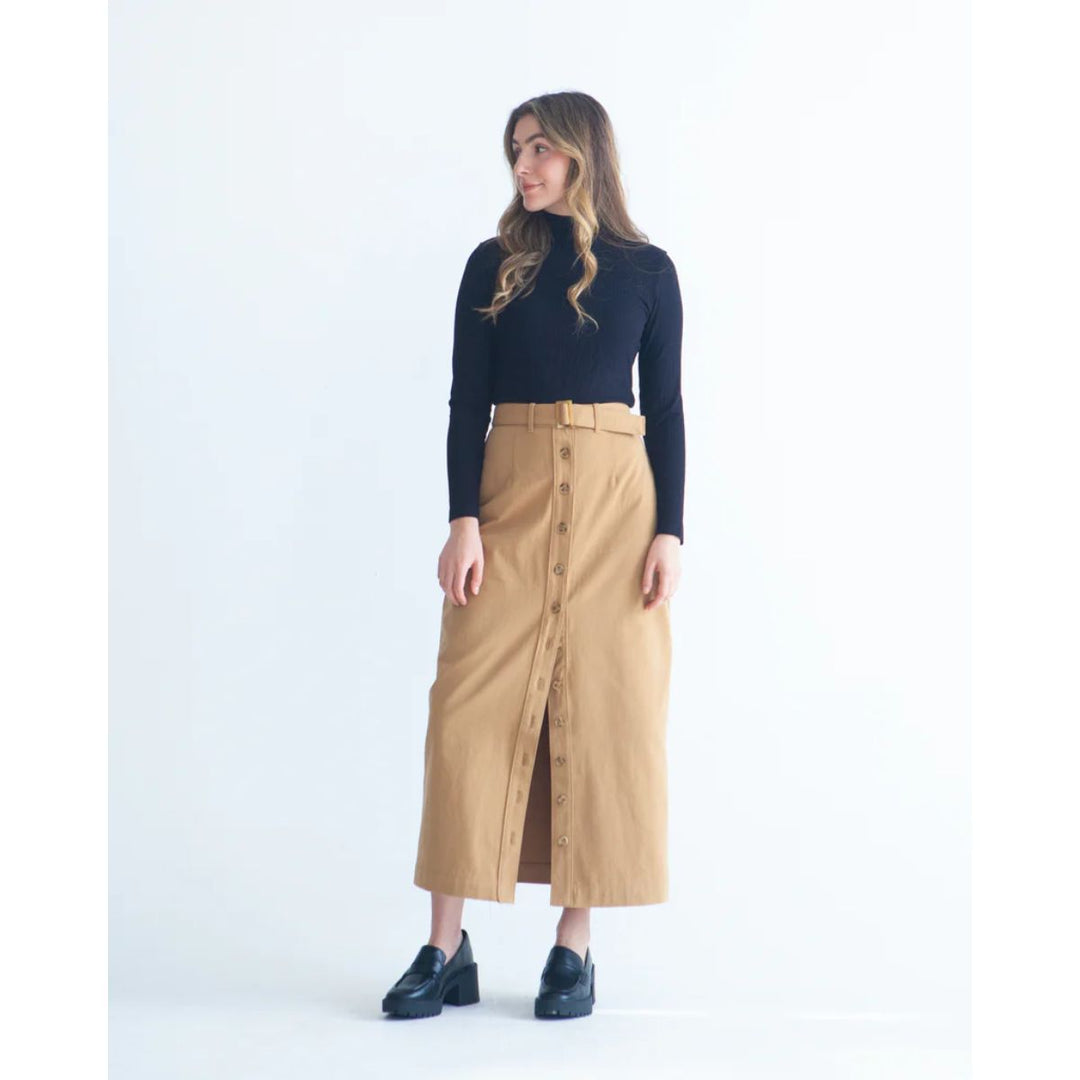 Woman wearing a black turtleneck and beige skirt on a white background