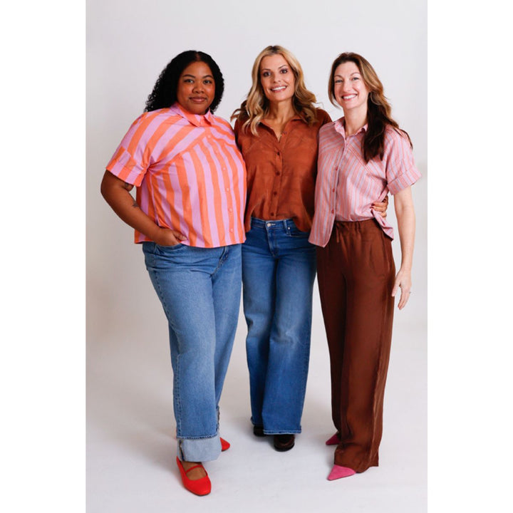 Three women wearing colorful shirts and jeans on a white background
