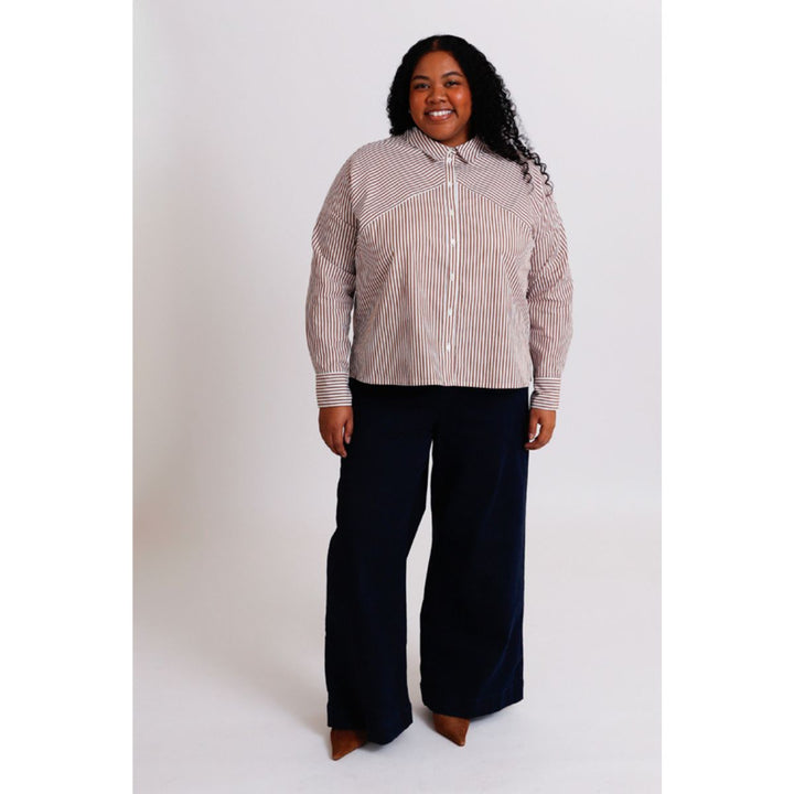 Woman wearing a striped shirt and dark pants on a white background