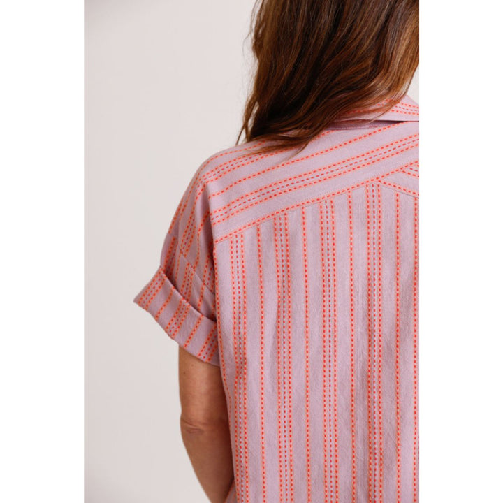 Person wearing a pink and orange patterned shirt on a plain background